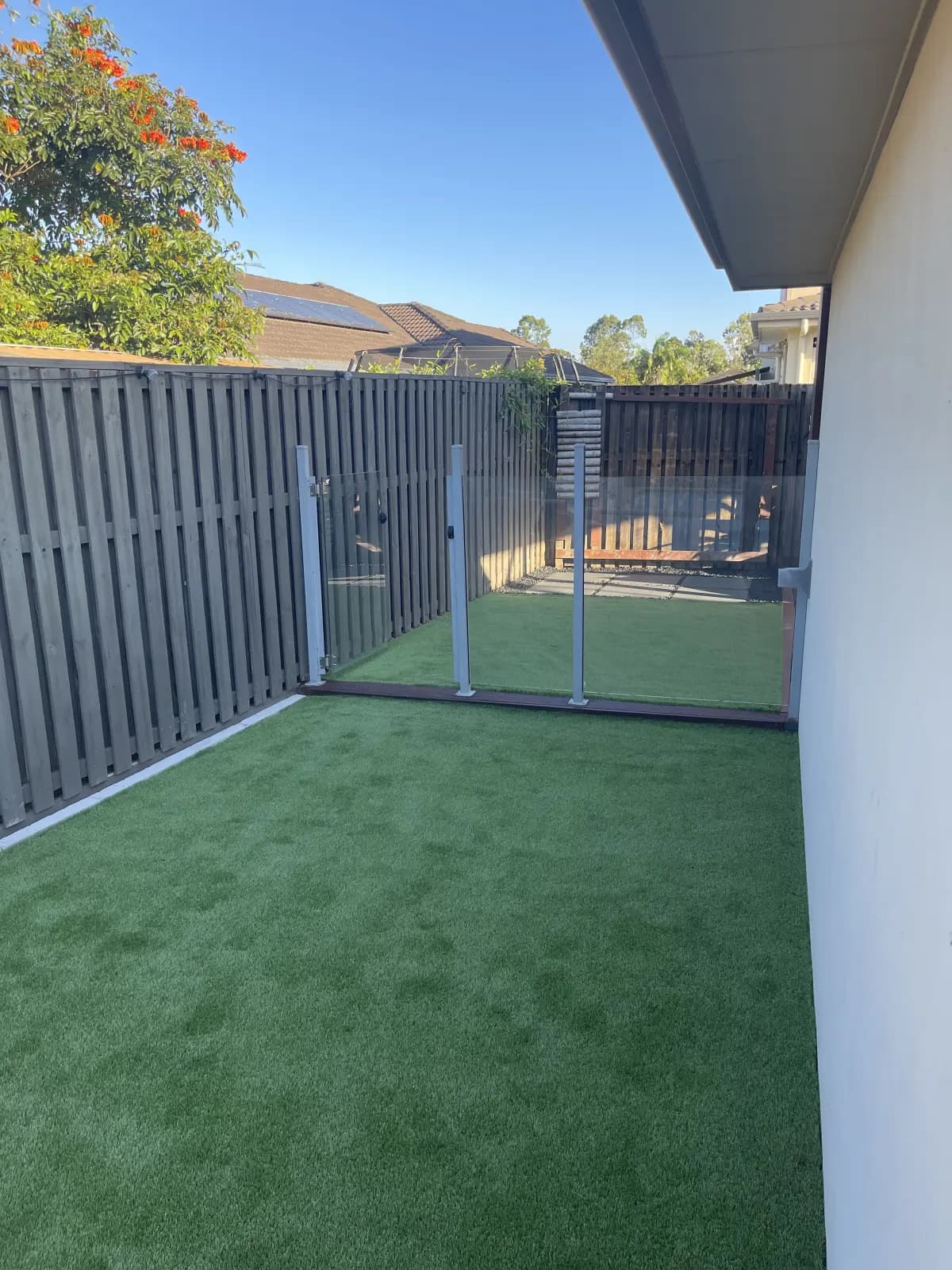Side yard with artificial turf and glass balustrade